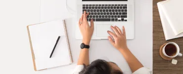 Entreprise individuelle: une personne travaillant sur un ordinateur portable dans un bureau, avec un bloc note, une tasse de café.