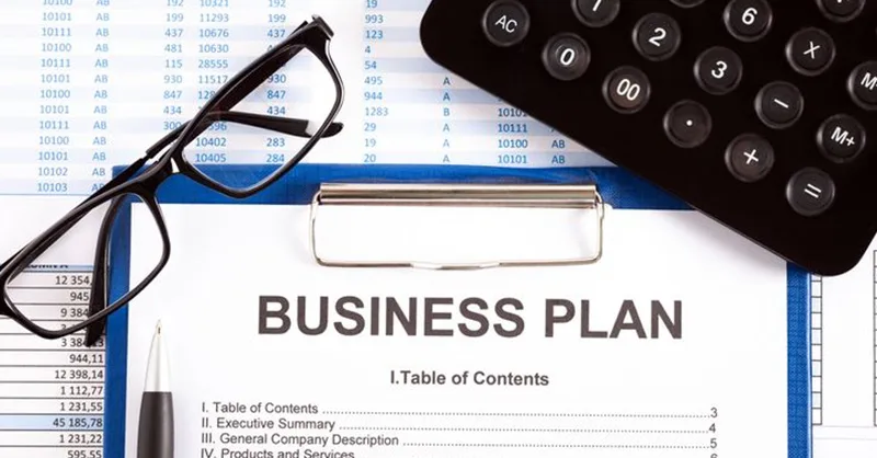 Image, photo d'un carnet ouvert avec un stylo, business plan en cours, avec des lunettes, une calculatrice.